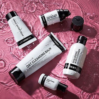 The Inkey List skincare products on a pink water surface.