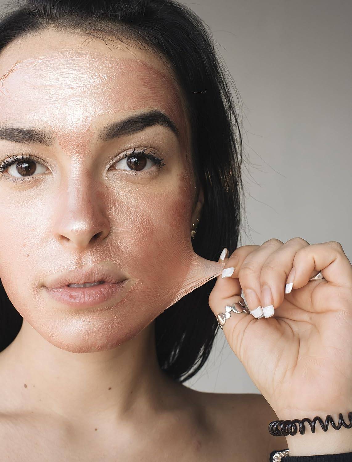 Woman peeling off Masque Bar Rose Gold Peel Off Mask, revealing smoother, glowing skin after detox and gentle exfoliation treatment.