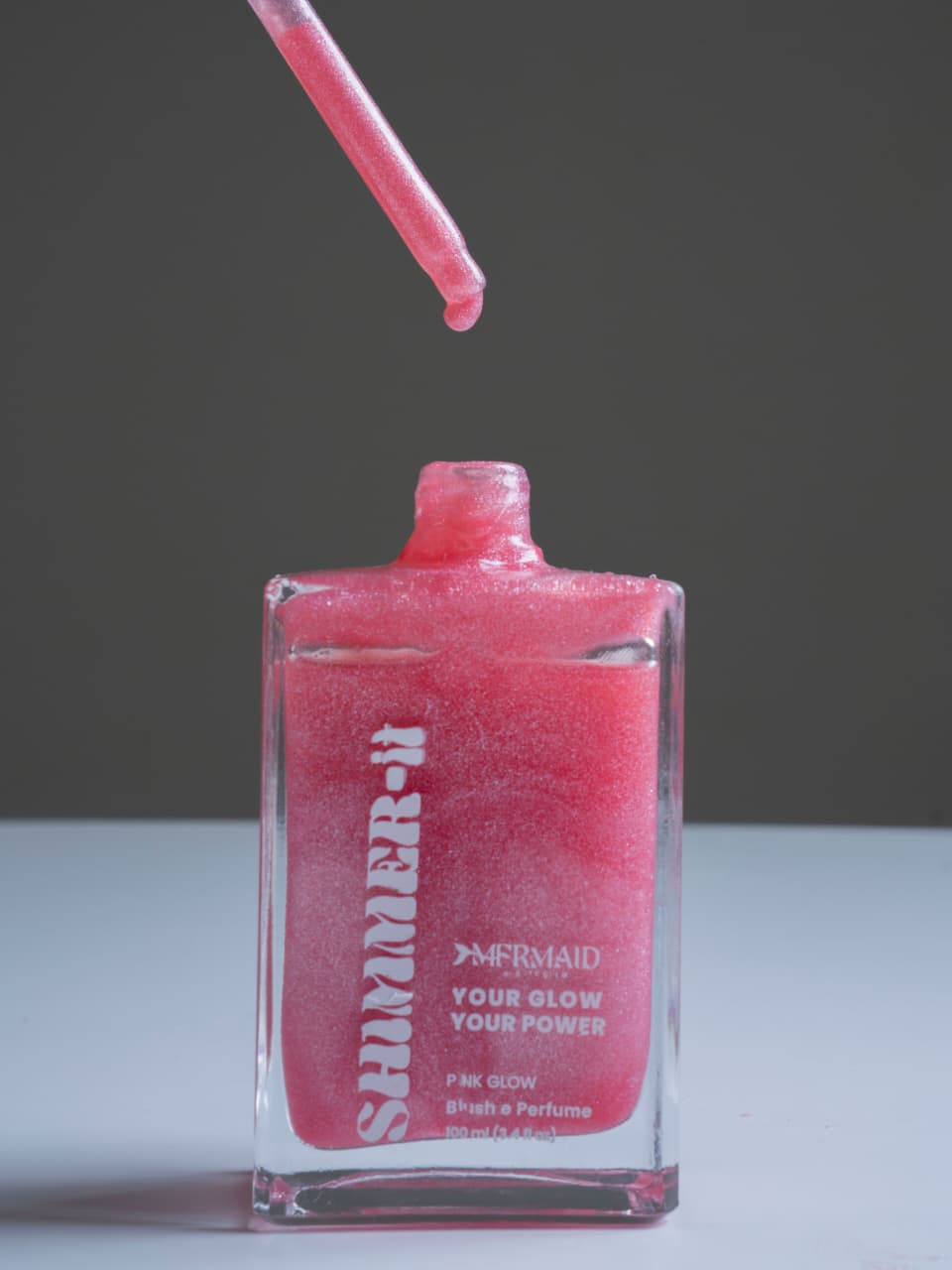 Close-up of Mermaid Pink Oil - Shimmering Body Oil with dropper releasing pink shimmer. Ideal for radiant skin and long-lasting hydration.