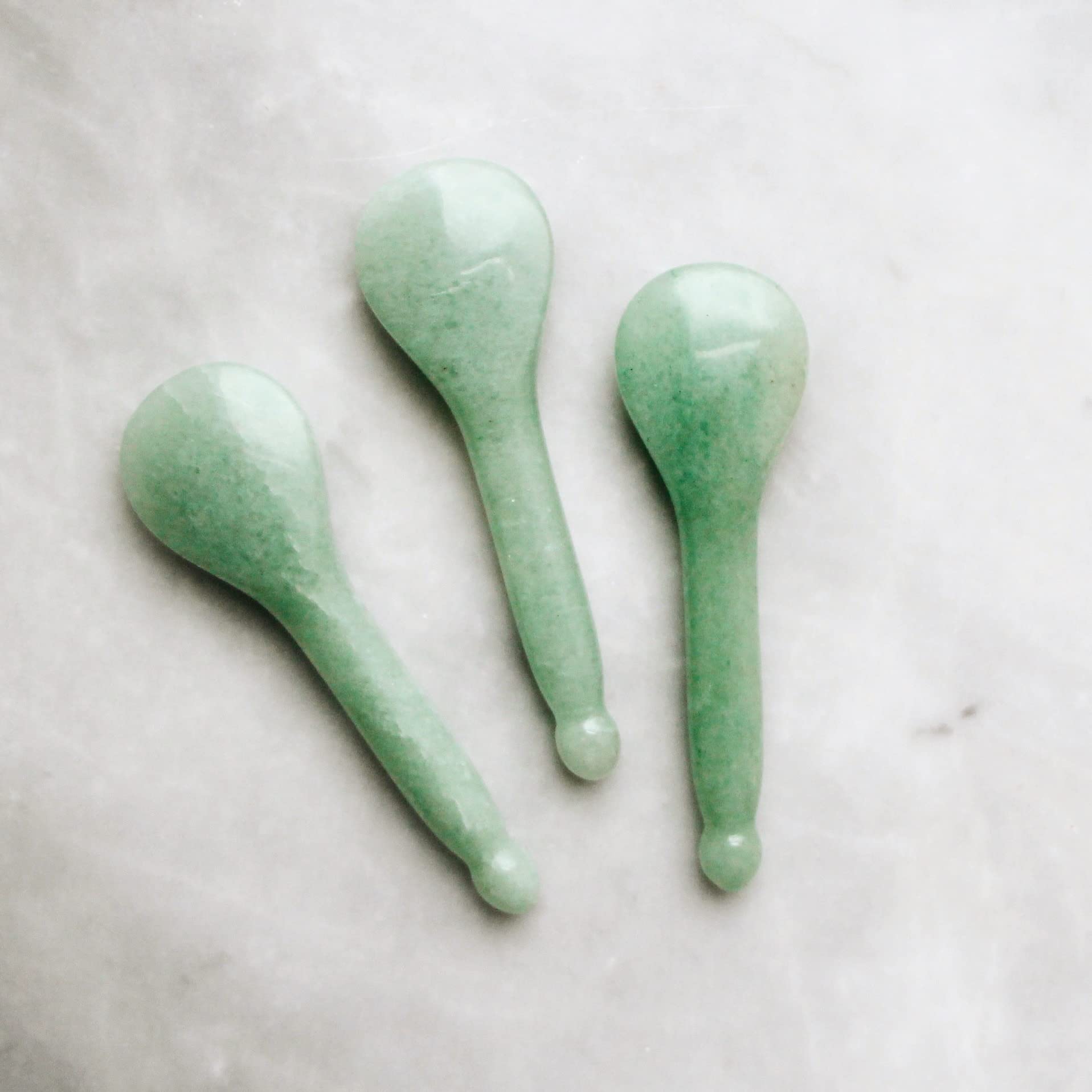 Three Mount Lai The Jade Acupressure Gua Sha Spoons made from genuine jade, displayed on a marble surface for skincare and wellness routines.