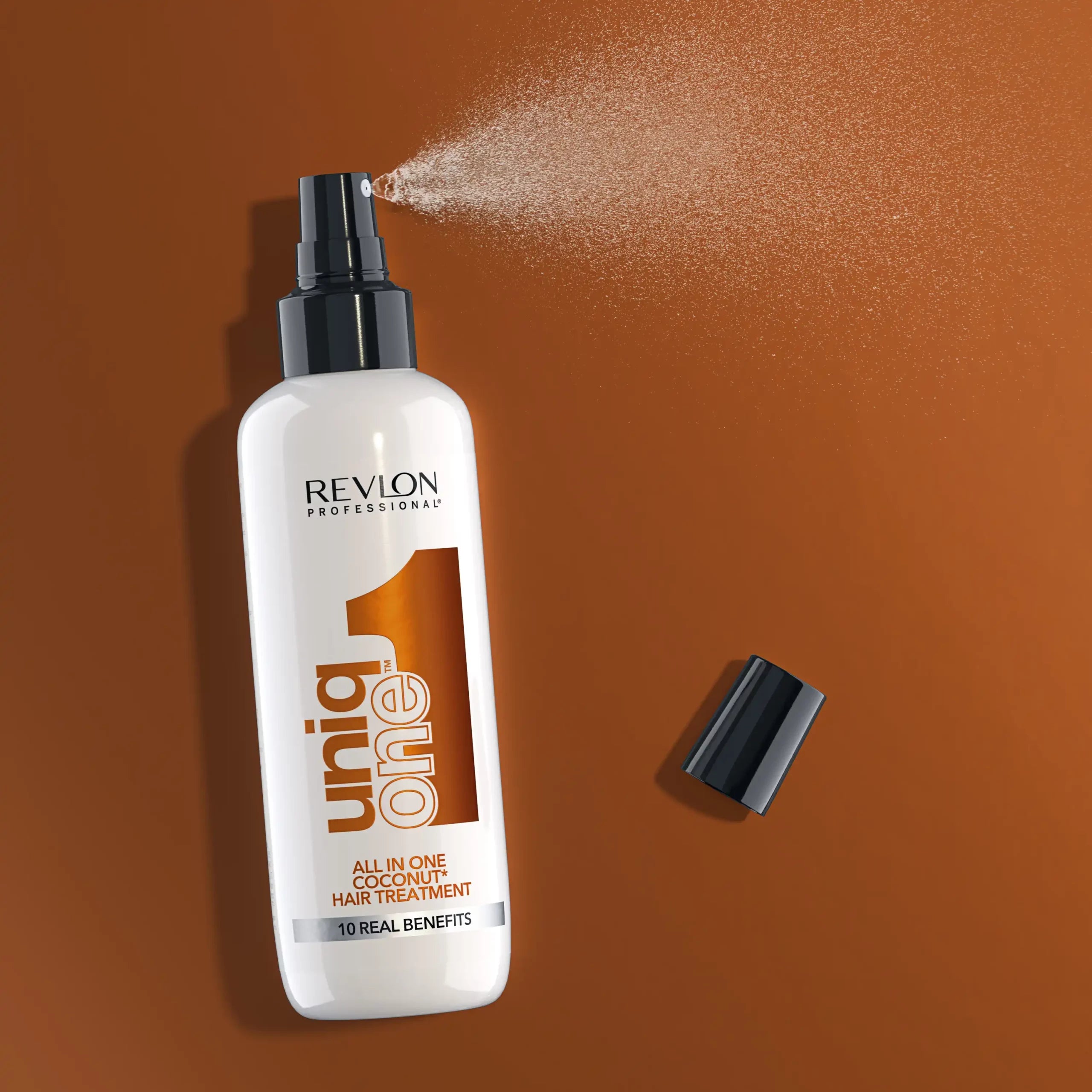 Revlon Uniq One leave-in treatment spray in action on a brown background, highlighting its easy application and coconut formula.