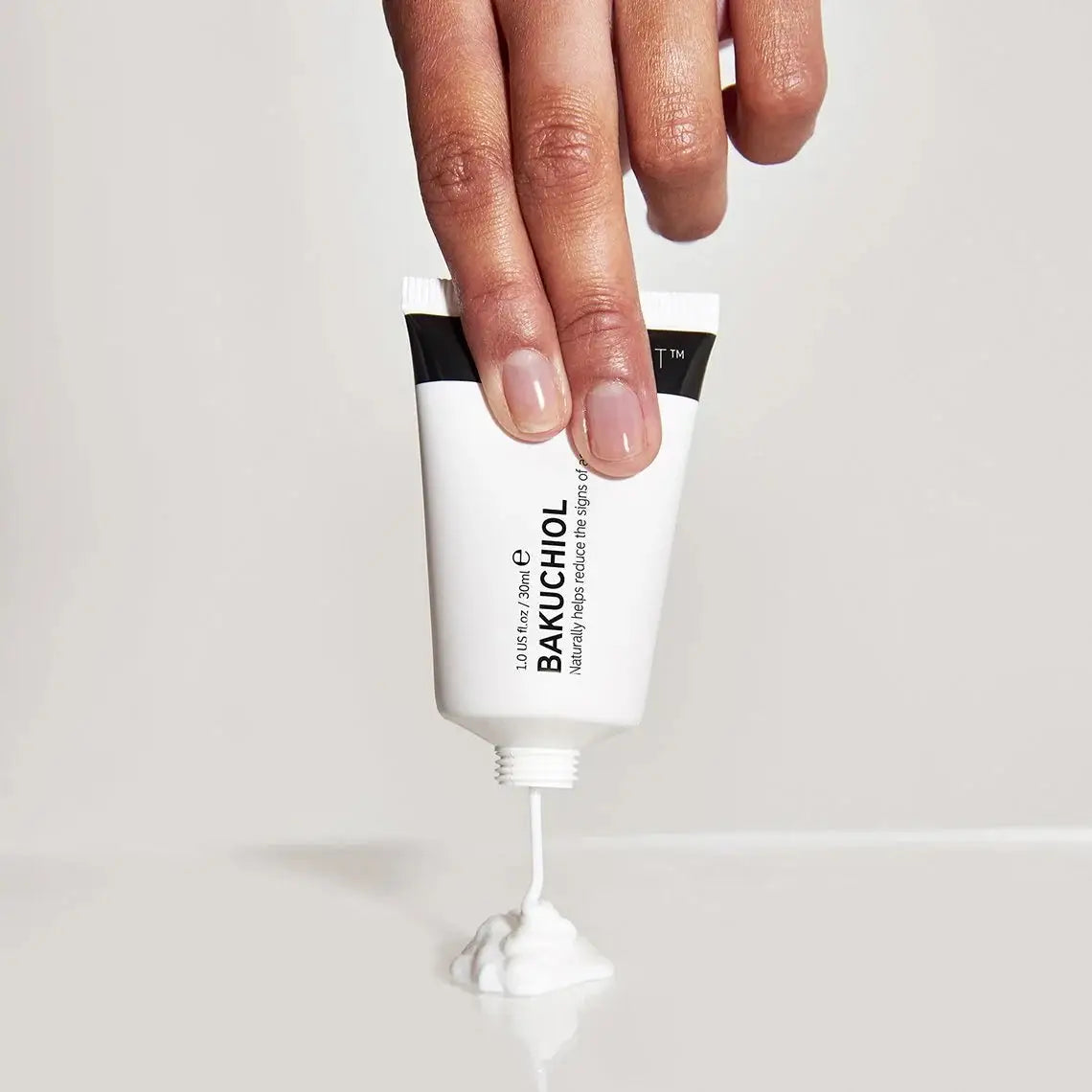A hand squeezing The Inkey List Bakuchiol Moisturizer 30 ml, dispensing a creamy formula. This anti-aging moisturizer helps reduce fine lines and wrinkles.