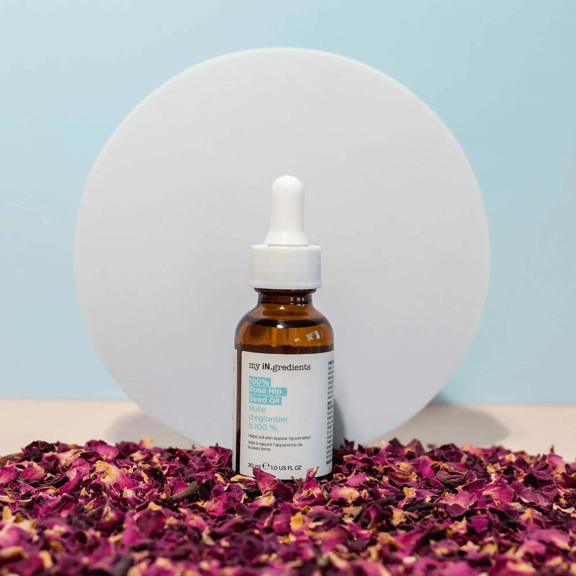 My iN.gredients Rosehip Seed Oil serum bottle placed on dried rose petals, promoting natural skincare and radiance.