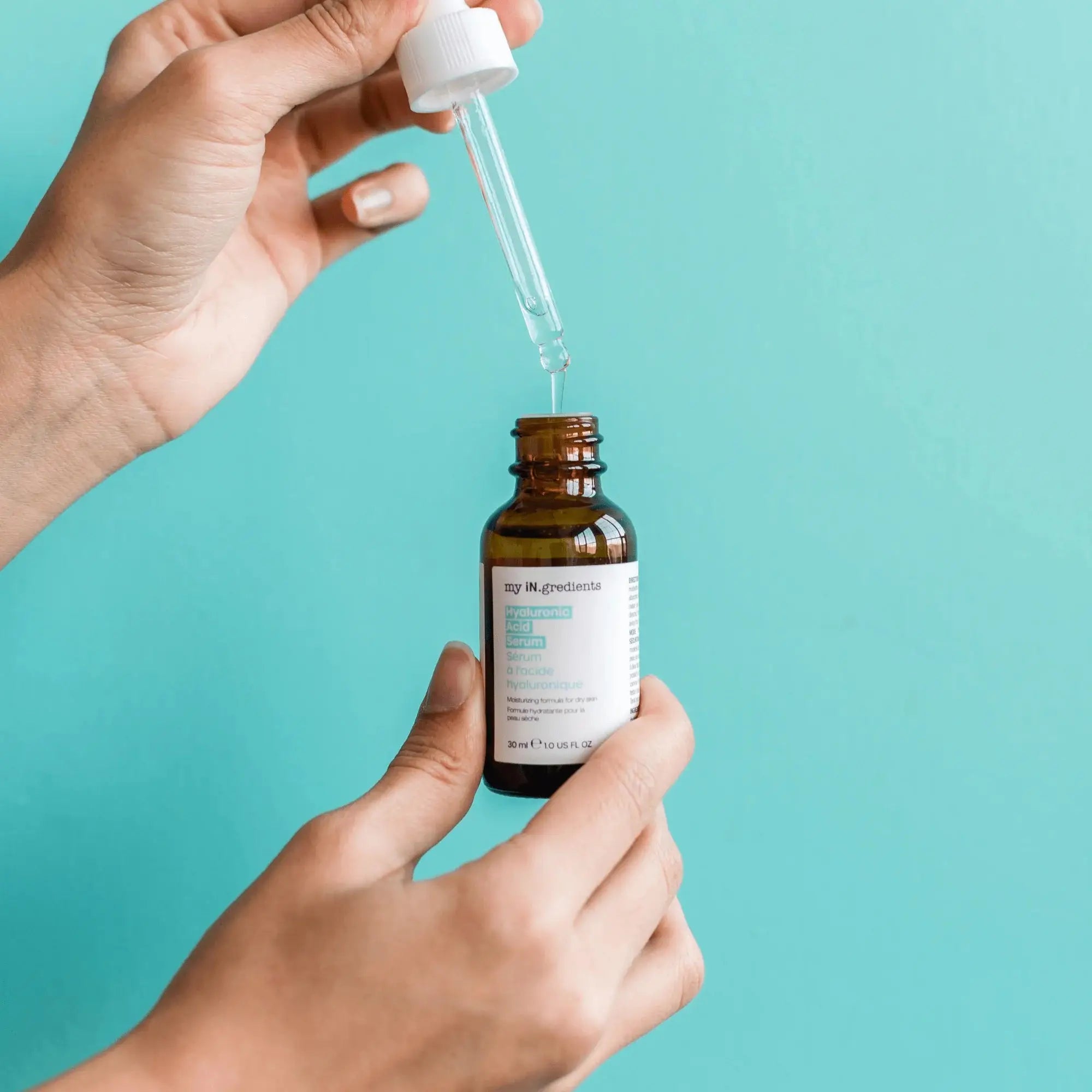 Hands holding My iN.gredients Hyaluronic Acid Serum dropper bottle, showcasing lightweight texture for sensitive skin and deep hydration.