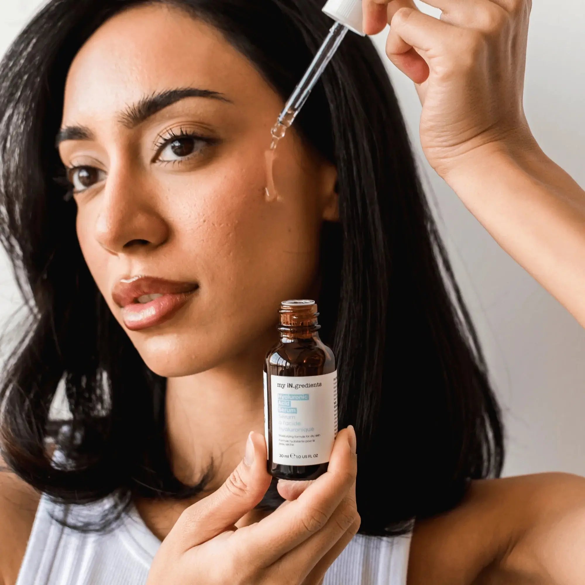 Woman applying My iN.gredients Hyaluronic Acid Serum with dropper, demonstrating skincare routine for hydrated, plump, and glowing skin.
