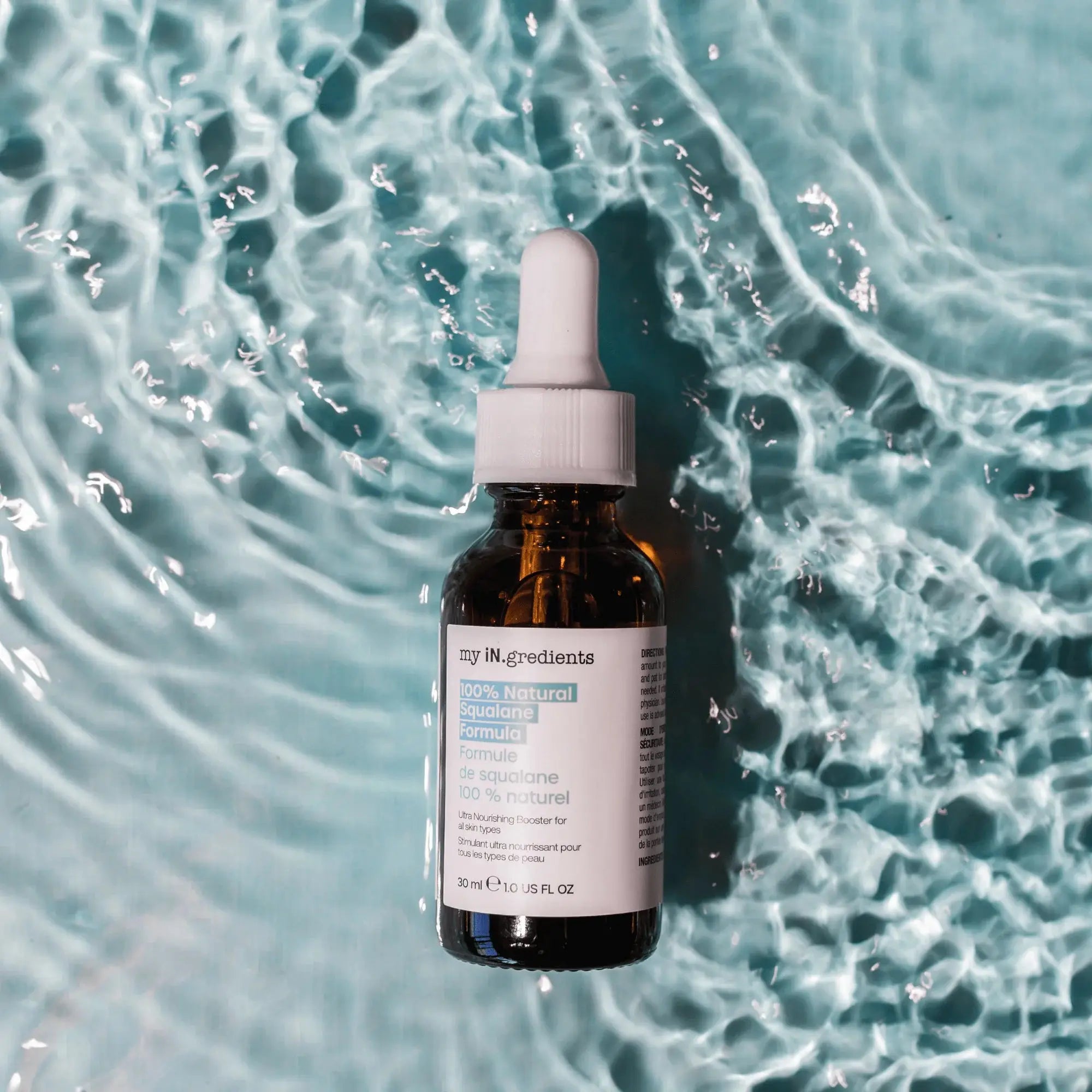 My iN.gredients Squalane Serum bottle placed on rippling water background, emphasizing hydration and natural skincare appeal.