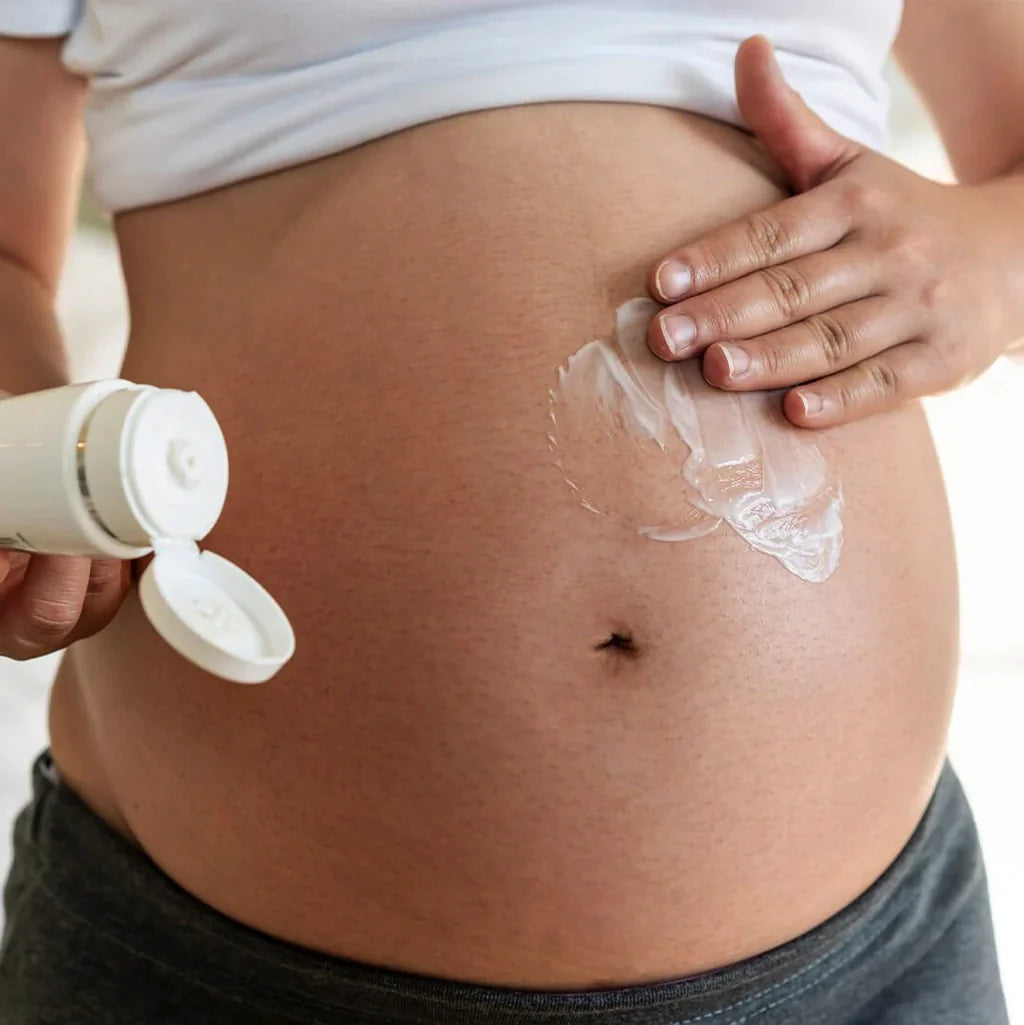 Pregnant woman applying stretch mark cream on belly.