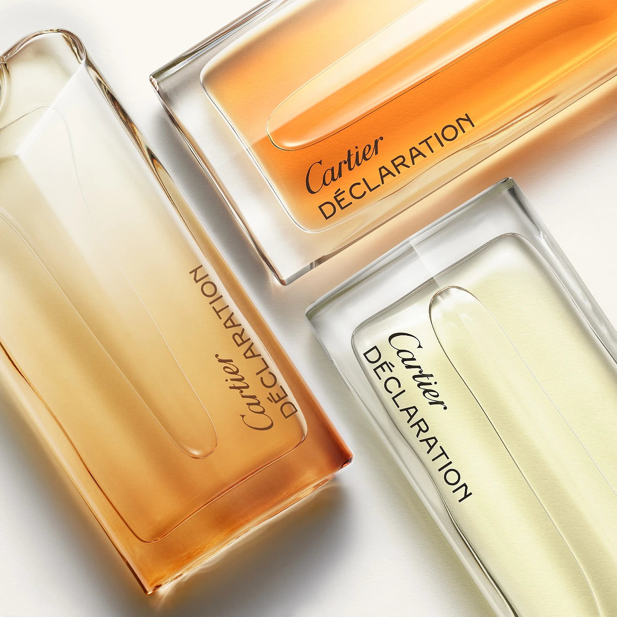 Cartier Declaration EDT men's fragrance trio in gradient glass bottles showcasing woody, musk, and citrus scent variations.