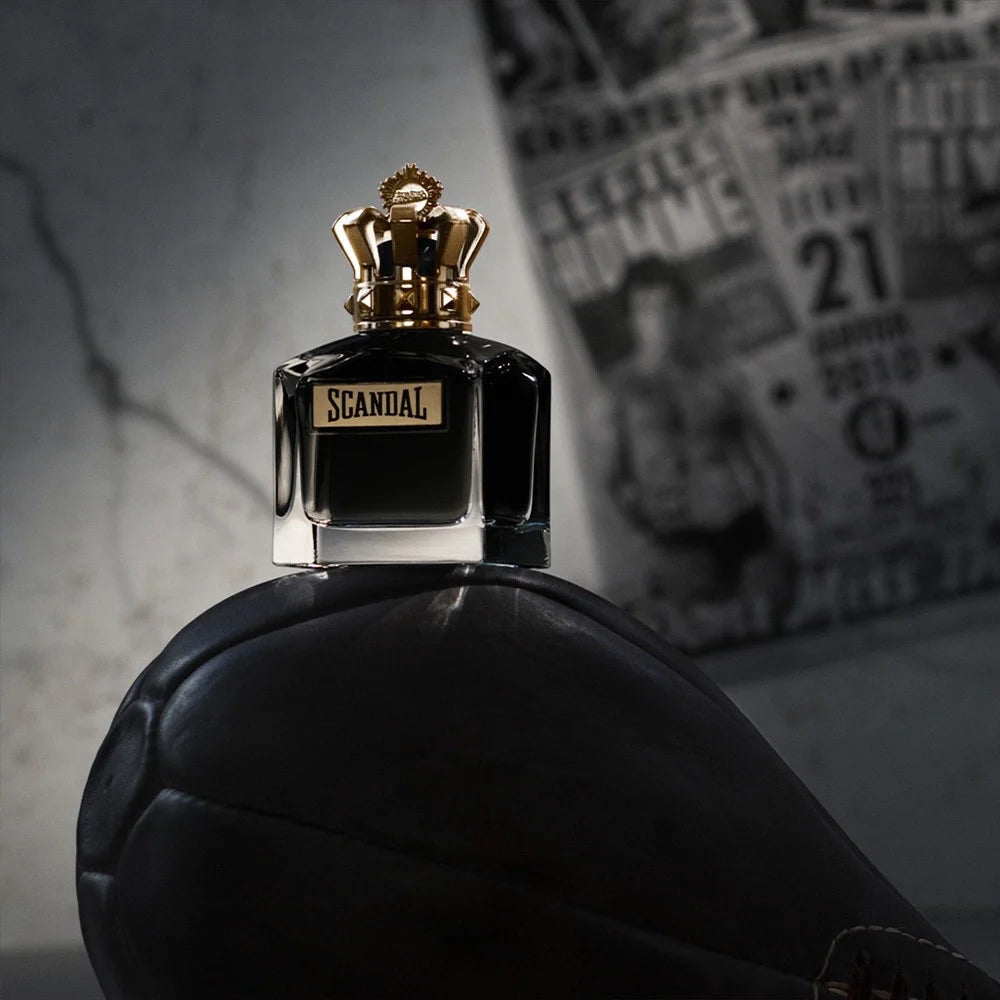 Jean Paul Gaultier Scandal Le Parfum EDP 100 ml bottle with gold crown cap displayed on a vintage boxing glove. Bold oriental men's fragrance.
