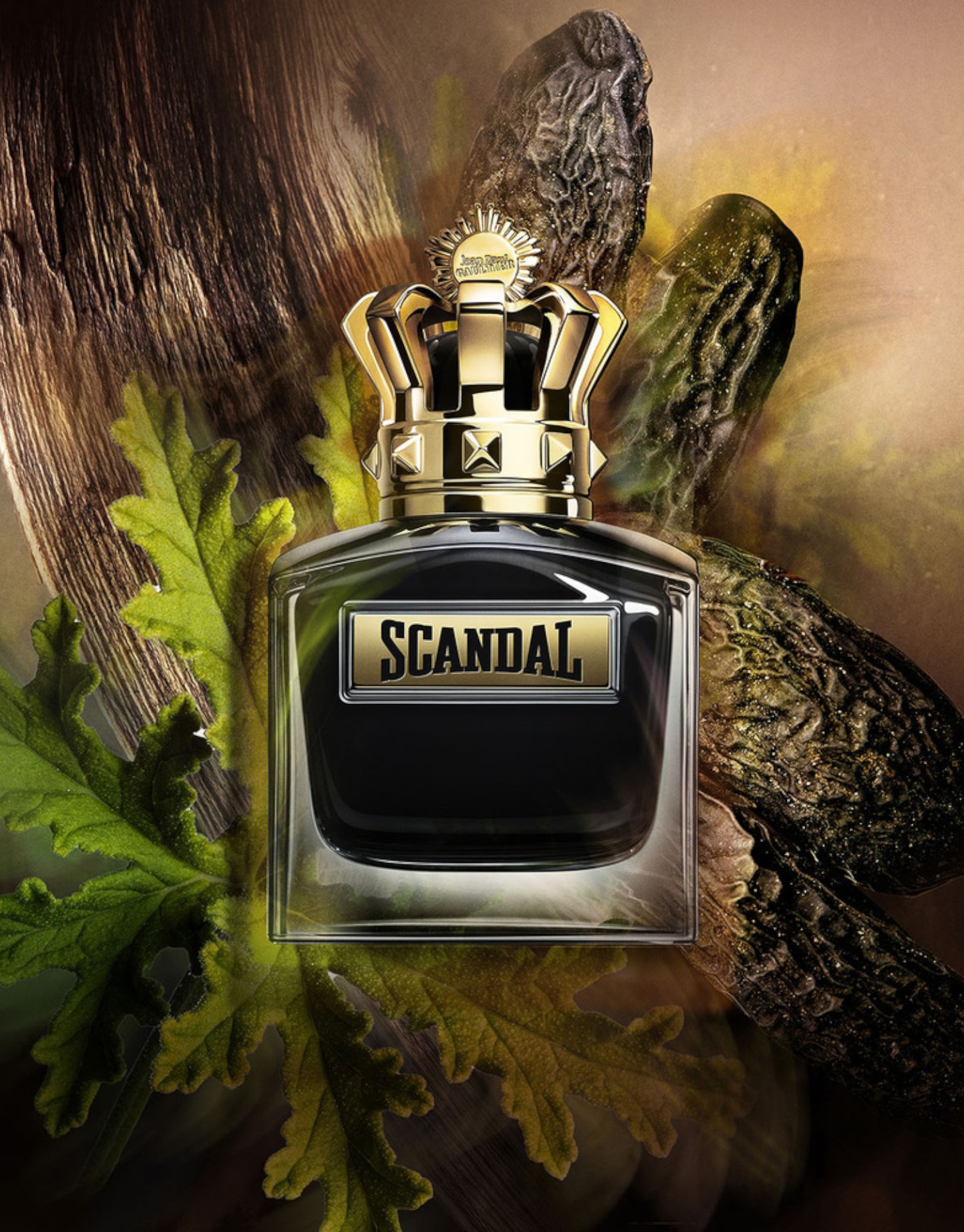 Scandal Le Parfum by Jean Paul Gaultier EDP 100 ml bottle surrounded by tonka bean and oak leaves. Oriental scent for men with rich woody notes.
