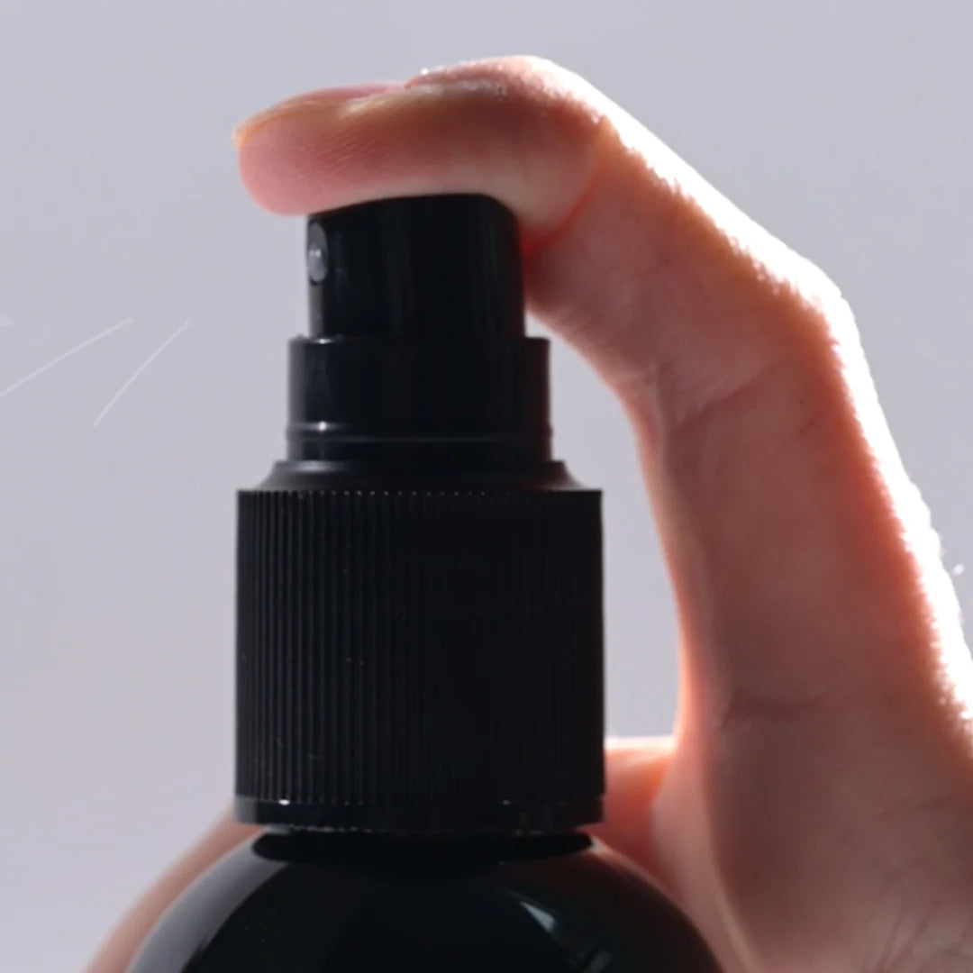 Close-up of Lazartigue Curl Spray nozzle being pressed, showcasing easy spray application for frizz control and curl definition.