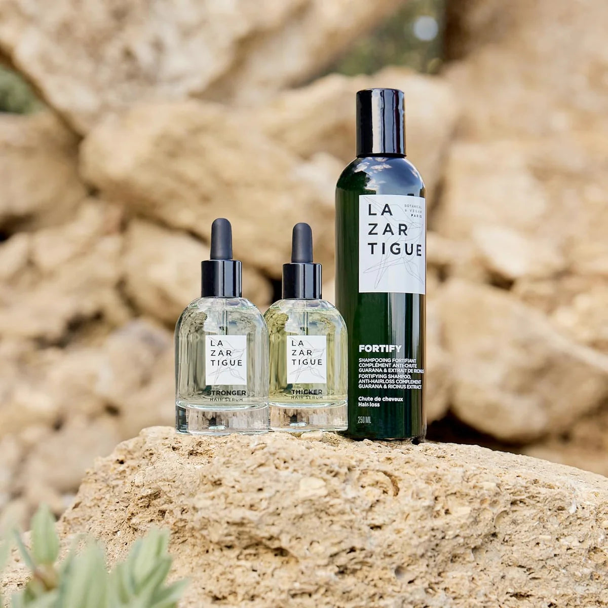 Lazartigue Fortify Shampoo displayed outdoors with hair serums, part of a natural hair loss treatment for thin and fragile hair.