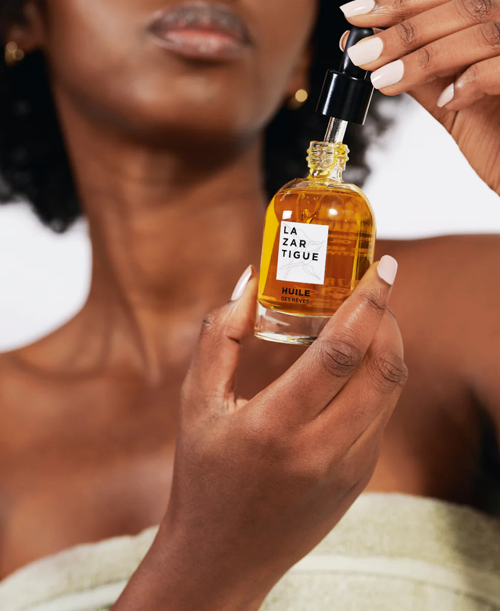 Woman applying Lazartigue Hair Oil - Nourishing Vegan Shine, a silicone-free botanical formula for healthy, radiant hair care.