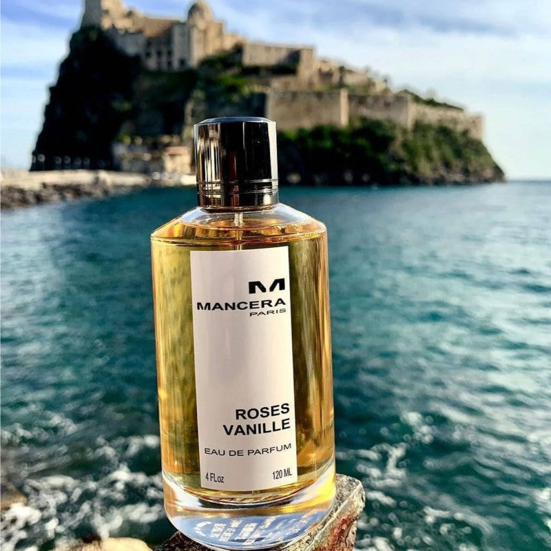Mancera Roses Vanille Eau De Parfum 120 ml placed by the sea with a scenic castle view, symbolizing its romantic and exotic fragrance.