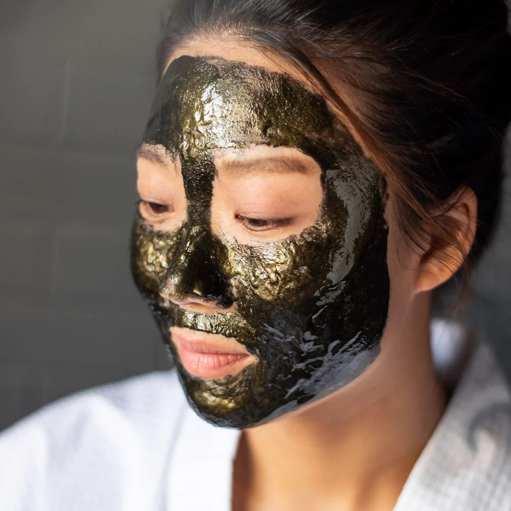 Woman wearing Masque Bar Black Gold 24K Peel-Off Mask for purifying and brightening skin. Perfect for detox and gentle exfoliation.