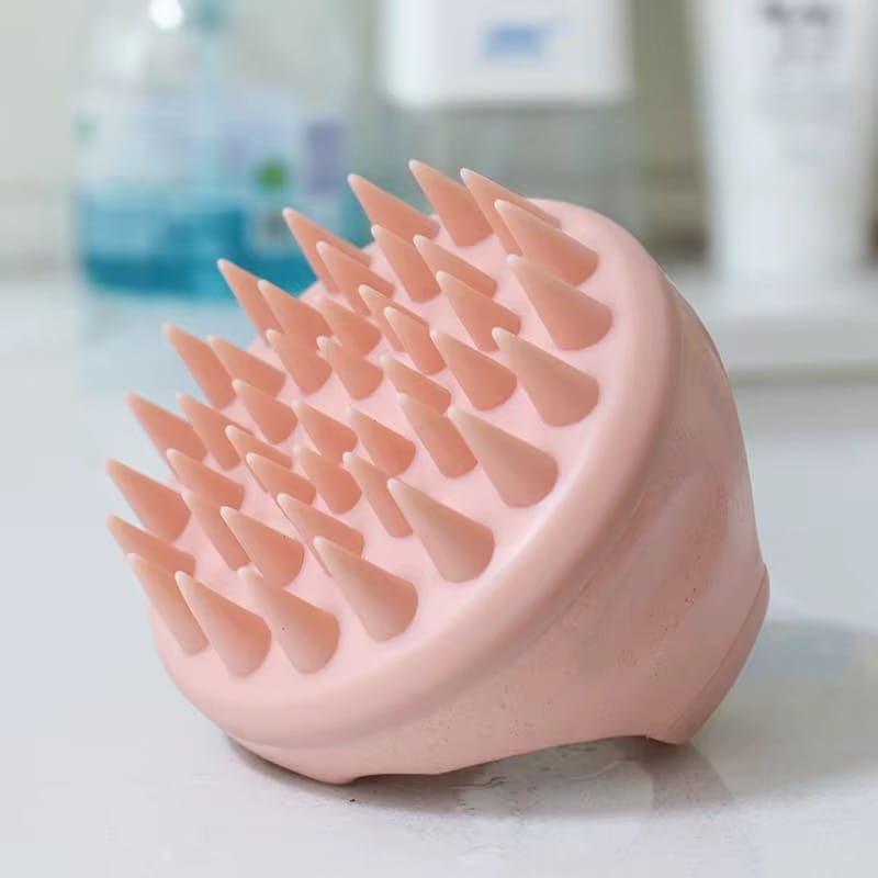 Close-up of Mermaid Scalp Massager on bathroom counter, showing flexible silicone tips for deep scalp exfoliation and improved hair growth.