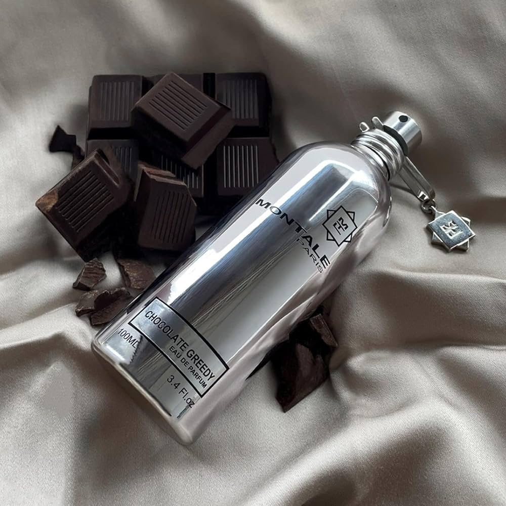 Montale Chocolate Greedy Eau De Parfum 100ml placed beside dark chocolate pieces, emphasizing its gourmand fragrance profile.