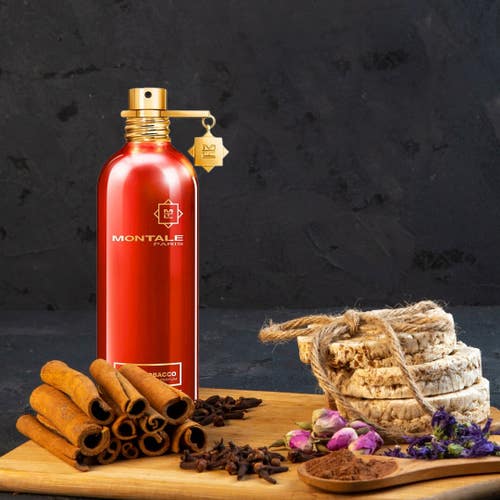 Montale Oud Tobacco Perfume bottle displayed with cinnamon, cloves, and floral elements, emphasizing its spicy and woody fragrance profile.
