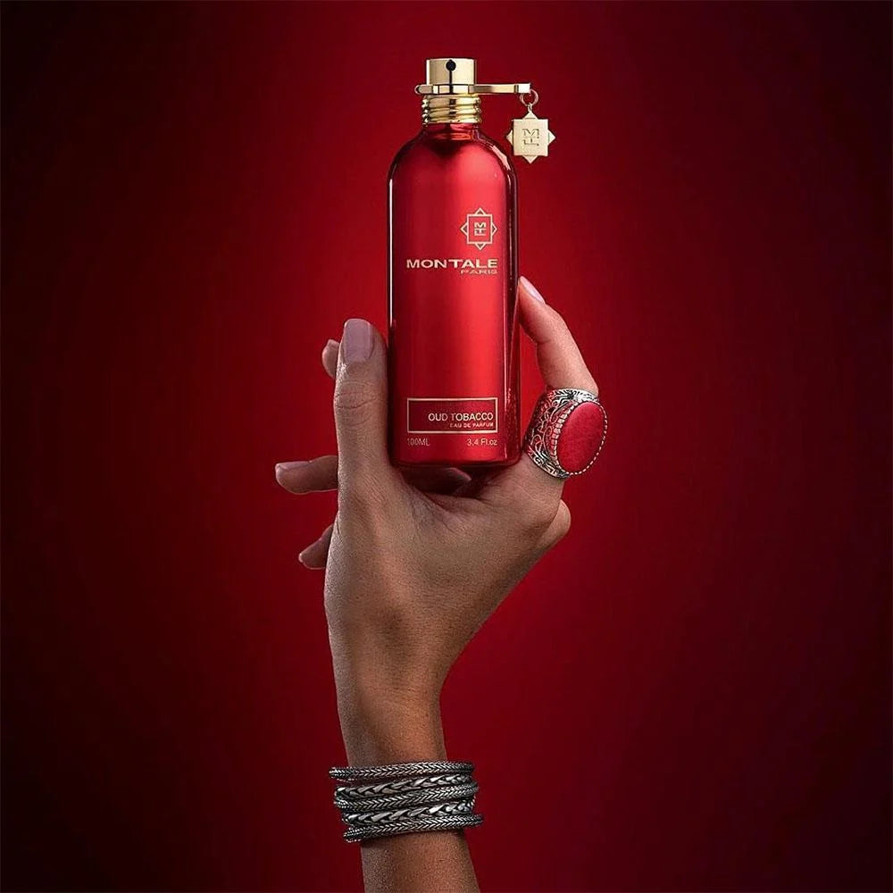 Hand holding Montale Oud Tobacco Perfume 100 ml, showcasing the elegant red bottle design ideal for men and women seeking a rich oud scent.