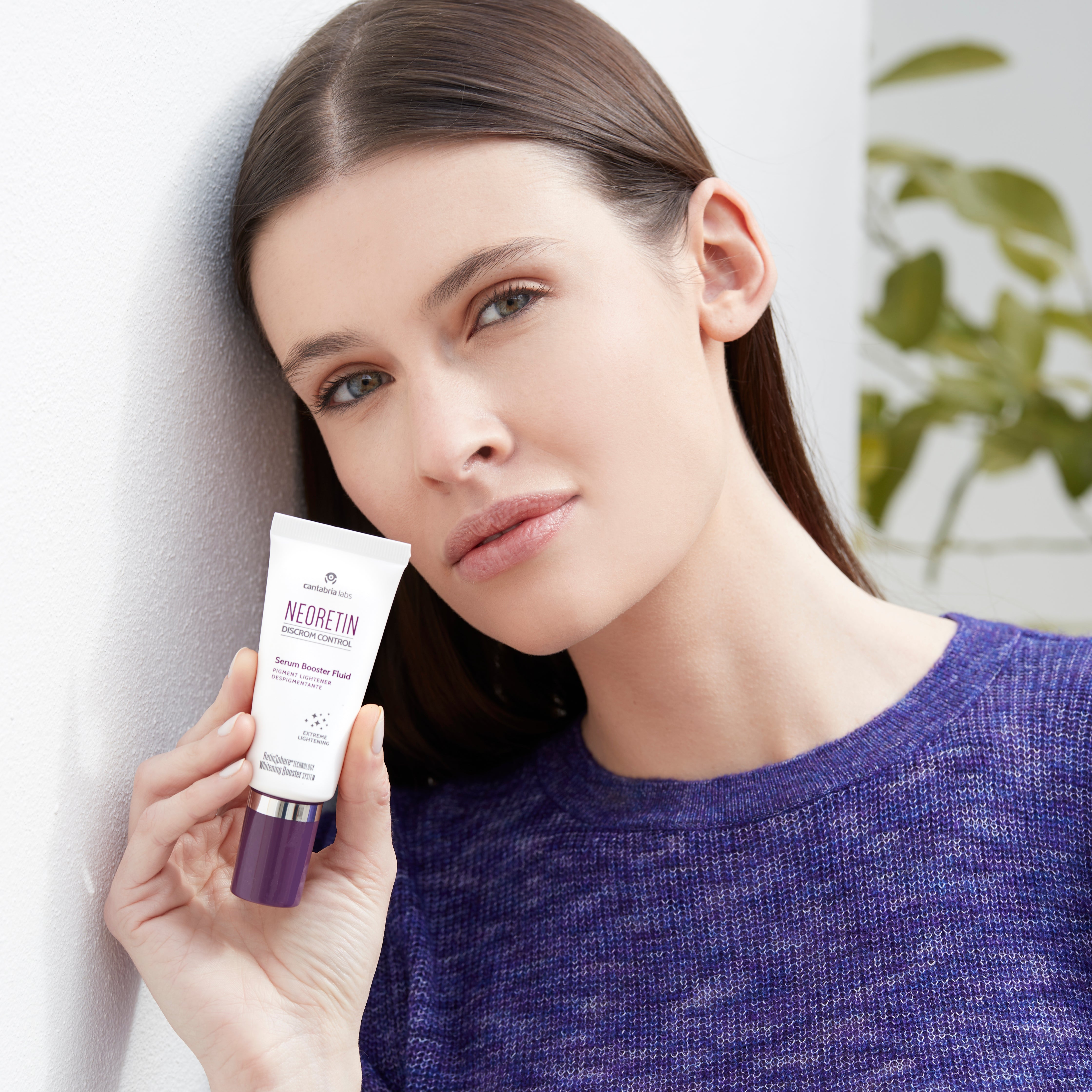 Woman holding Neoretin Discrom Control Serum Booster Fluid 30ml, promoting skincare for sensitive skin and dark spot reduction with Niacinamide.