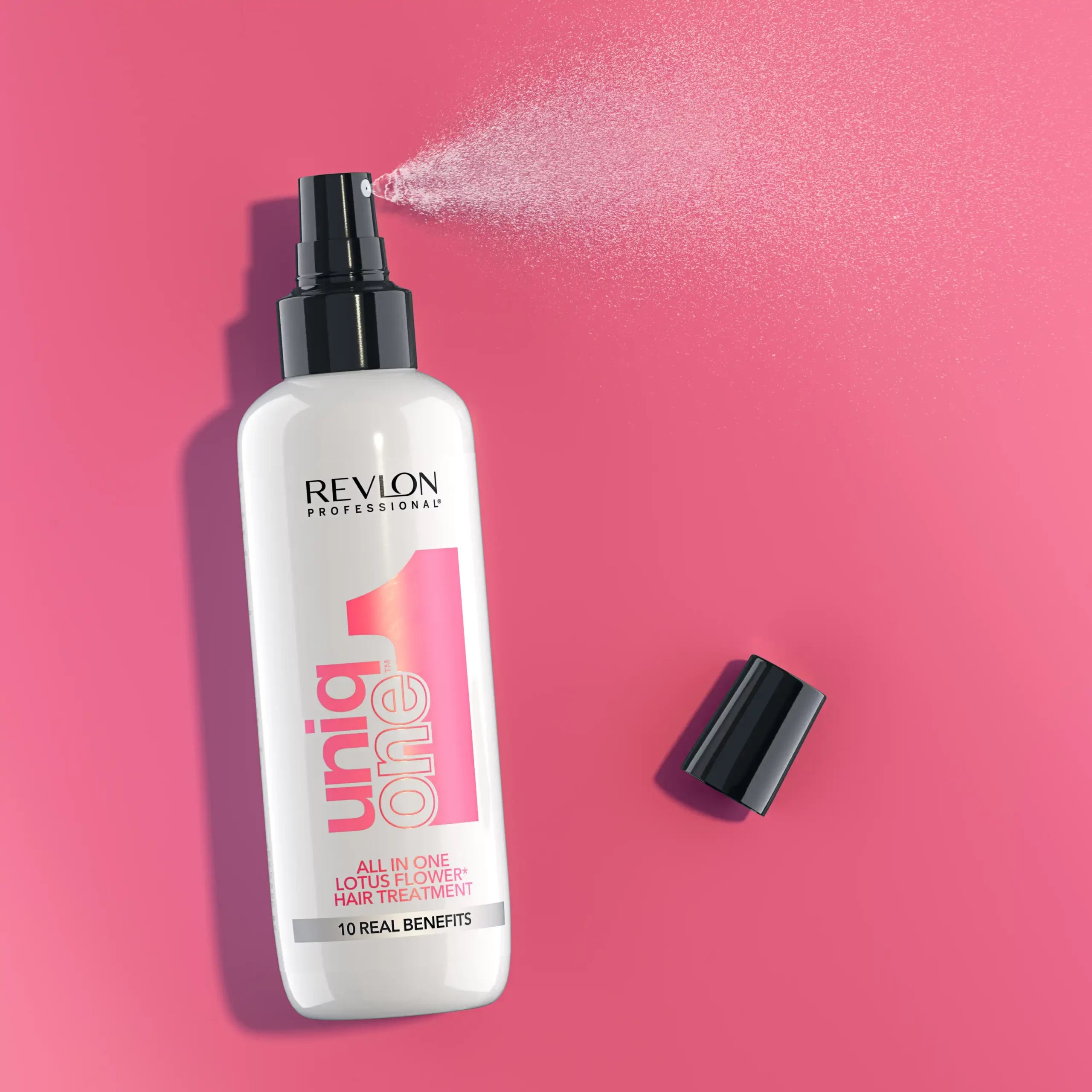 Revlon Uniq One Leave-in Treatment 150 ml spraying mist on pink background, ideal for frizz control and heat protection.
