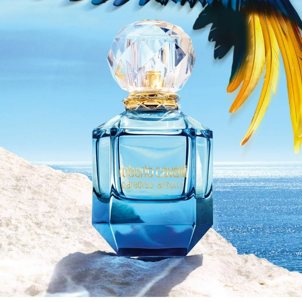 Roberto Cavalli Paradiso Azzurro Fragrance - Floral Aquatic | 75 ml bottle placed on a beach setting with ocean view, evoking Mediterranean freshness.