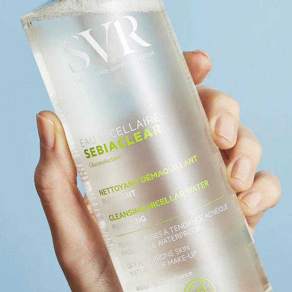 Hand holding SVR Sebiaclear Micellar Water bottle, highlighting its purifying formula for oily and acne-prone skin with Gluconolactone.