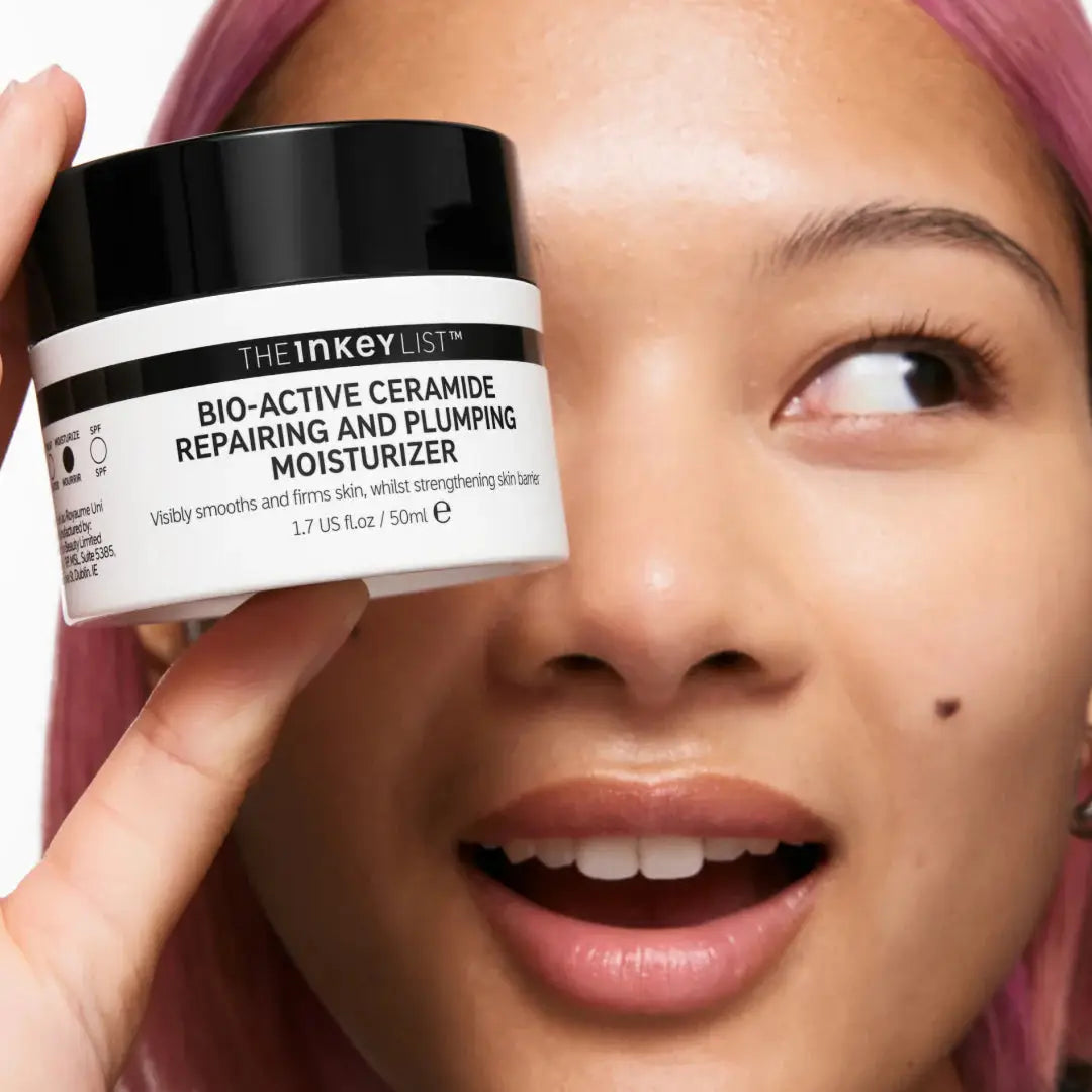 A smiling woman holding The Inkey List Bio-Active Ceramide Moisturizer, highlighting its benefits for strengthening the skin barrier and reducing fine lines.