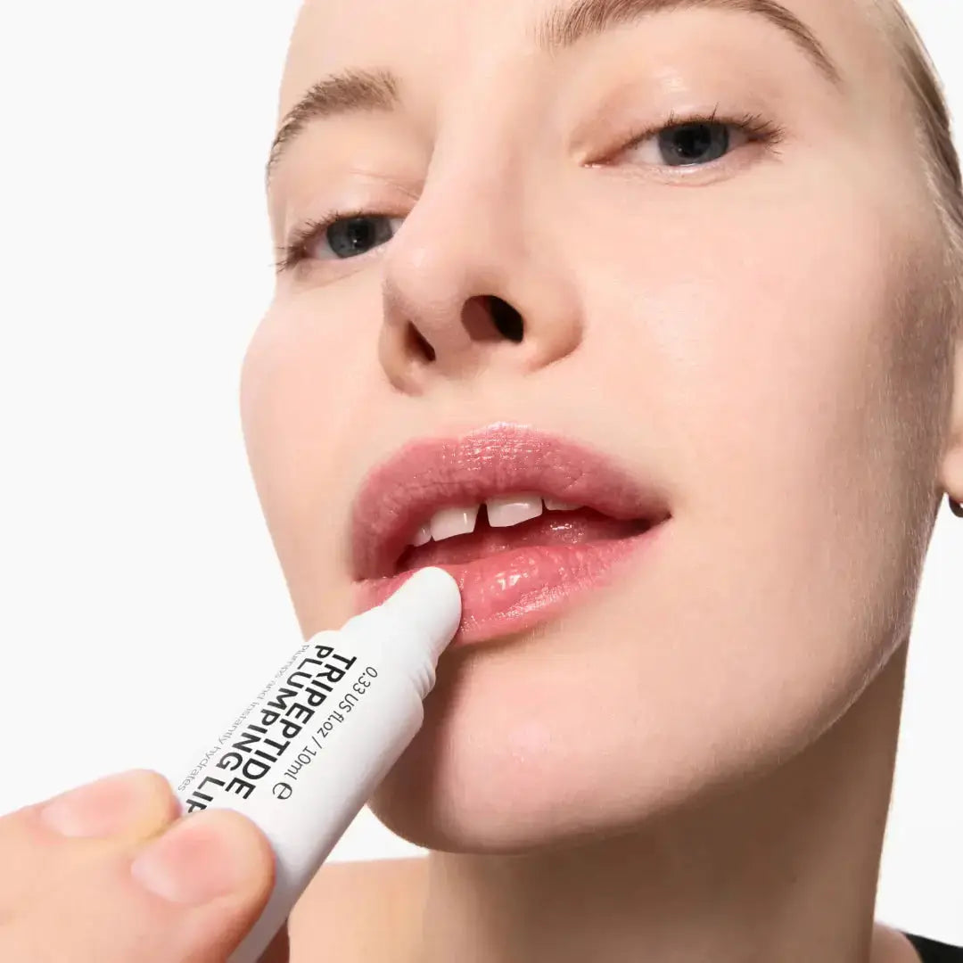 Model applying The Inkey List Tripeptide Plumping Lip Balm Pink Tint. Hydrating and plumping formula enhances lip volume and smoothness.