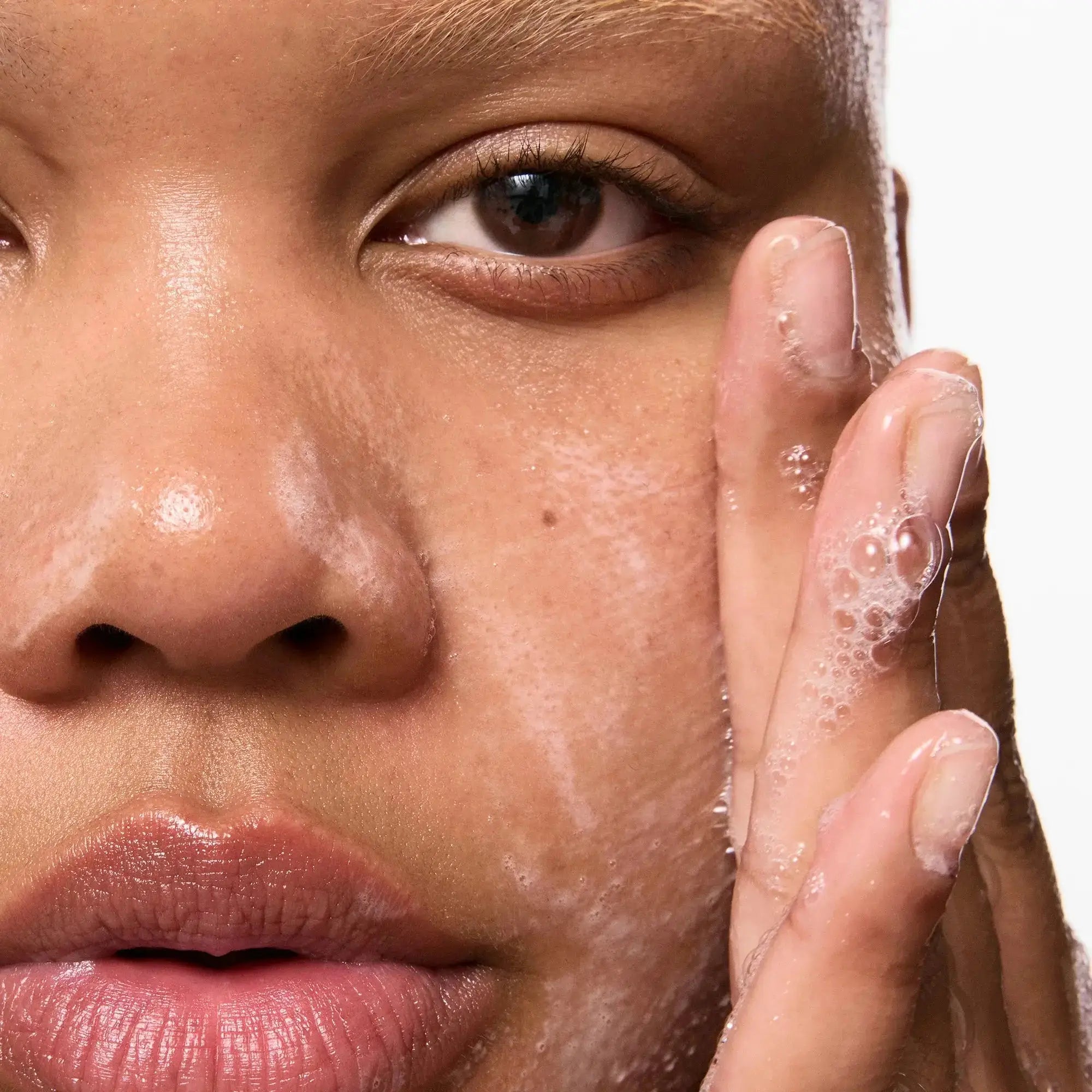 Close-up of a person washing their face with The Inkey List Salicylic Acid Cleanser, demonstrating its foamy lather and gentle cleansing.