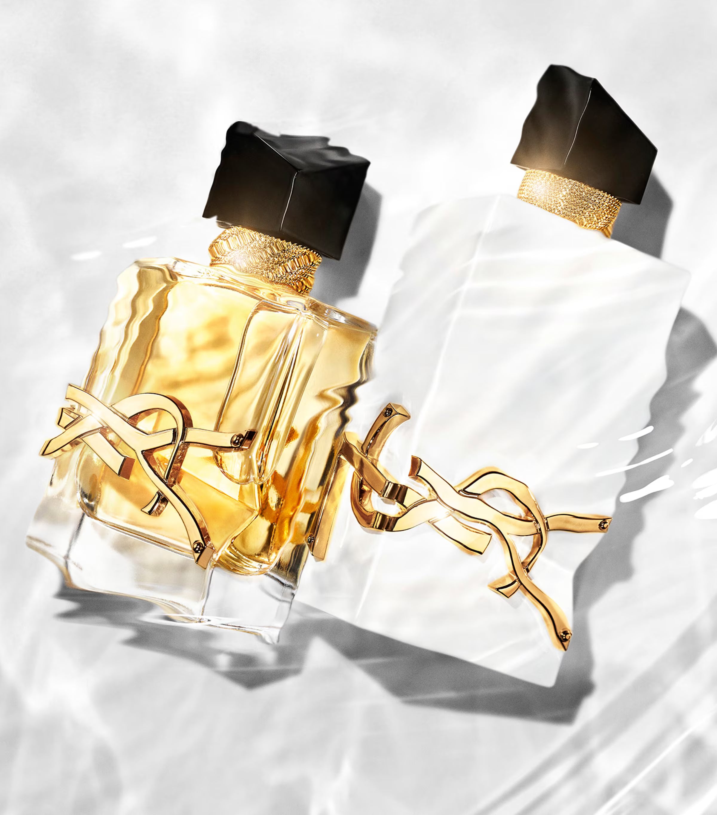 YSL Libre L'Eau Nue and original Libre perfume bottles in water, emphasizing the fresh, alcohol-free citrus scent and luxury design.