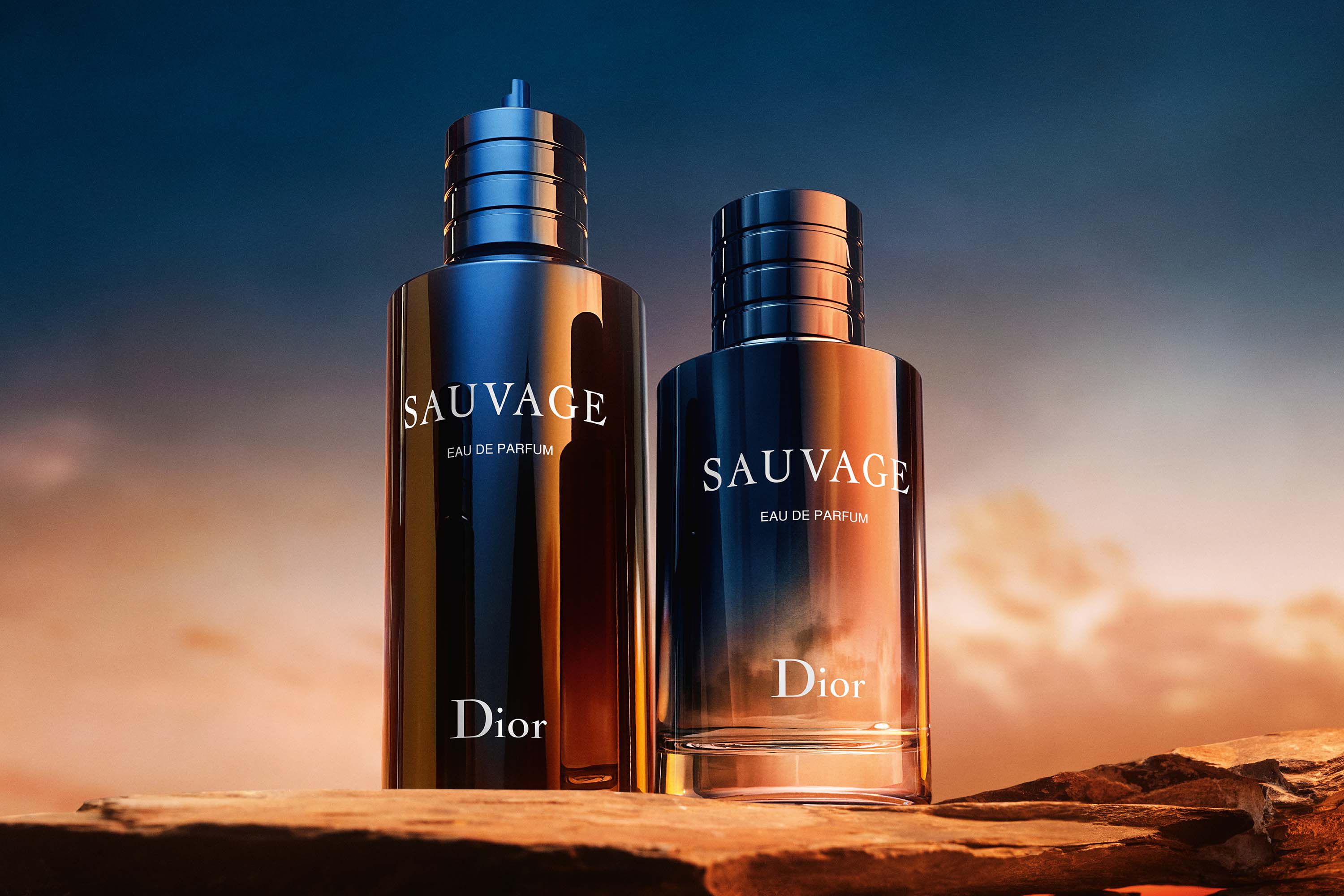 Two Dior Sauvage Eau de Parfum 100ml bottles displayed on rocks at sunset, showcasing the spicy vanilla scent in a premium setting.