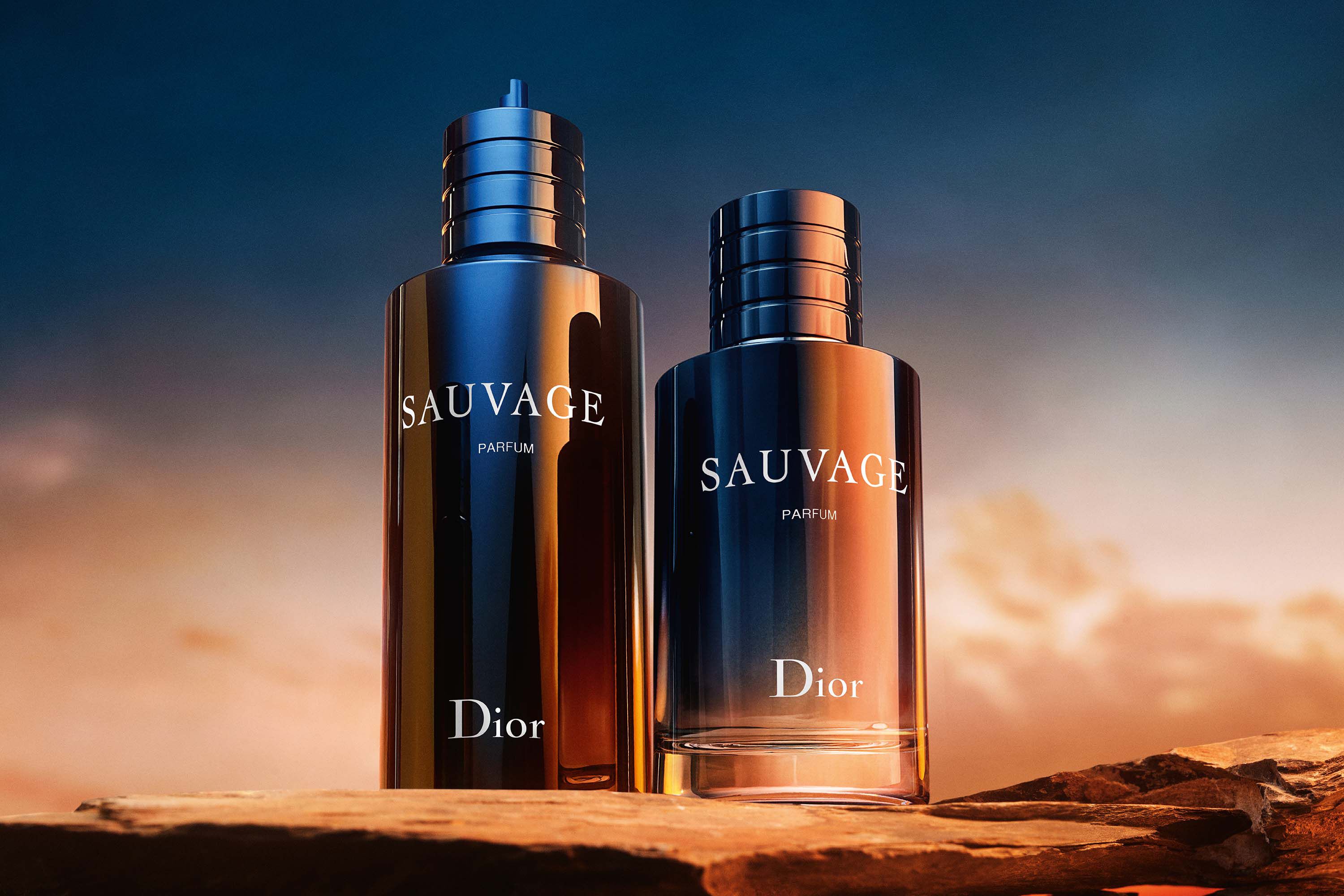 Two sizes of Dior Sauvage Perfume - 100ml Eau de Parfum displayed on rocky terrain at sunset, emphasizing its bold, masculine appeal.