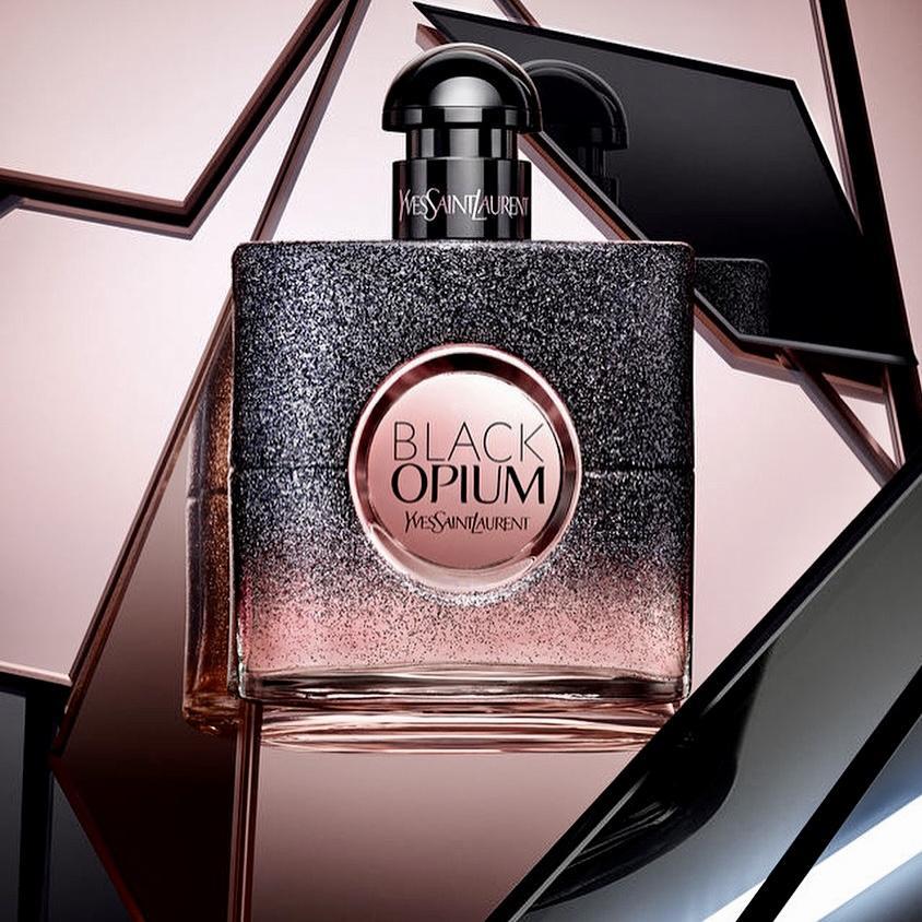 YSL Black Opium Floral Shock Eau de Parfum in a reflective setting, showcasing its shimmering bottle design and luxurious feminine fragrance.