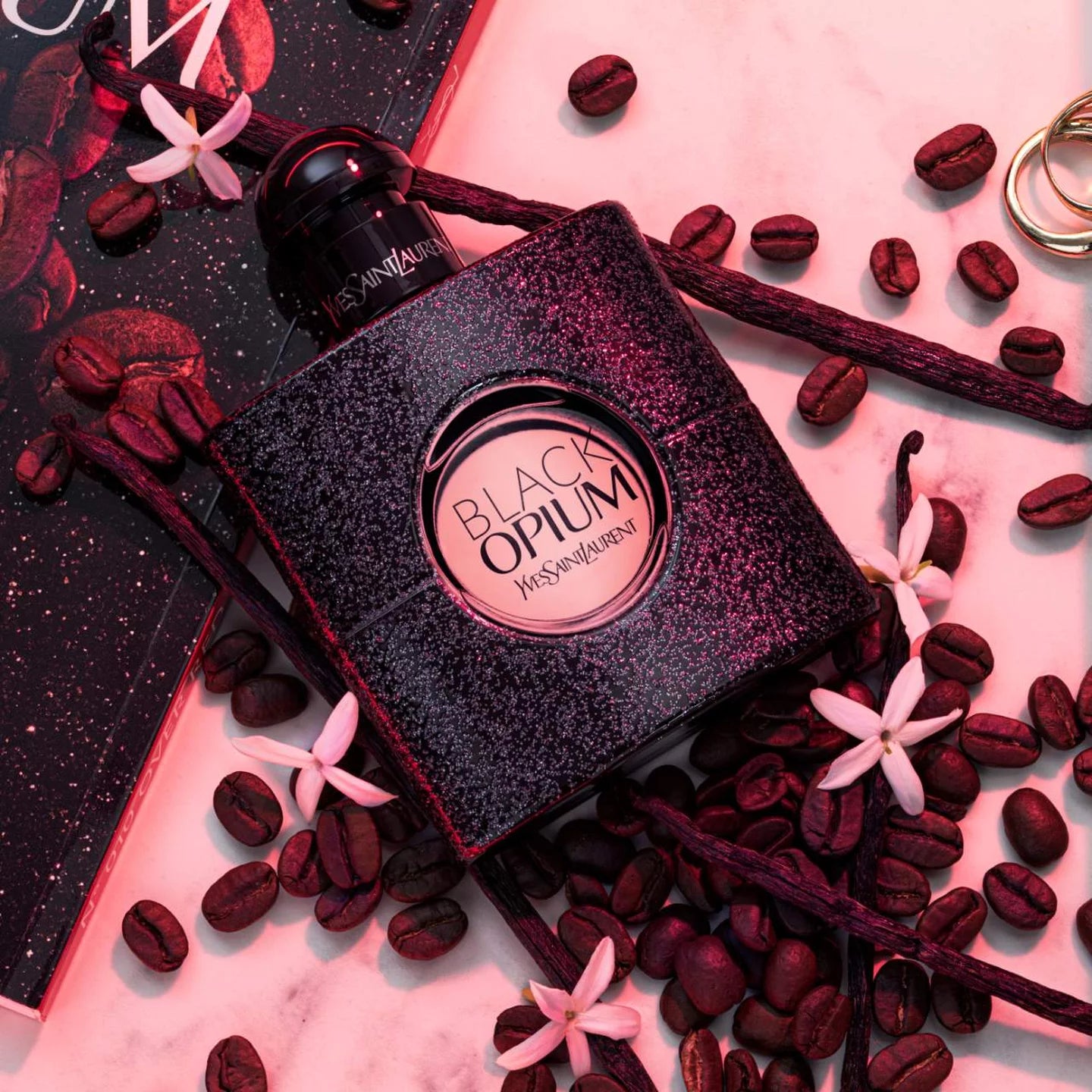 YSL Black Opium Floral Shock perfume bottle surrounded by coffee beans and white flowers, highlighting iced coffee and floral scent notes.